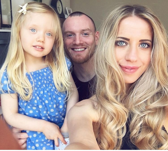 A young couple Amy and Joel pose with their very young daughter for a selfie.