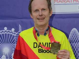 An older middle-aged man - David - poses with his marathon medal.