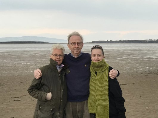 A group shot of Jasmine and her mum and dad on a windswept beach near the Wirral