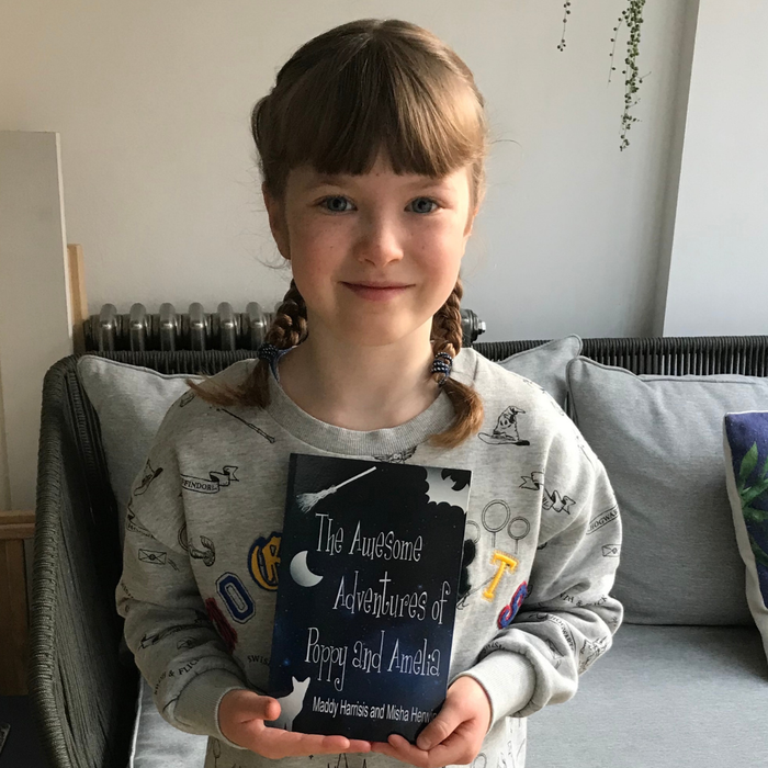 A young girl Maddy poses with a book - The Awesome Adventure of Poppy And Amelia.