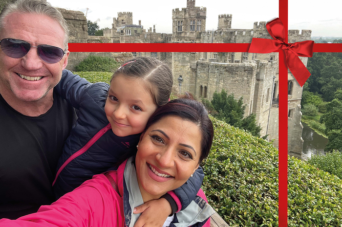 A family poses for a group selfie on holiday, in front of a castle.