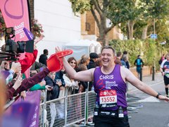 A runner high fives a supporter during a marathon. He wears a Blood Cancer UK T shirt.