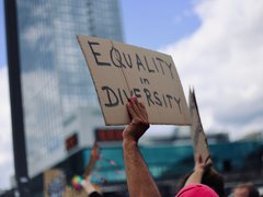 At a protest march, marchers hold up a sign with Equality and Diversity written on it.