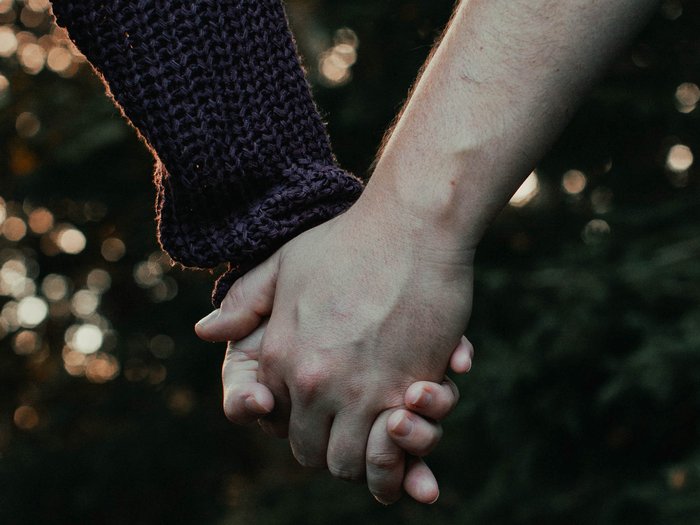 A couple hold hands - the image focuses on their hands.