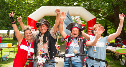 Bloodwise fundraisers in fancy dress as pirates, cheering at the finish line of a marathon