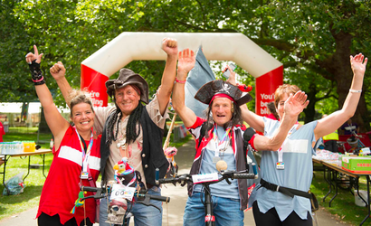 Bloodwise fundraisers in fancy dress as pirates, cheering at the finish line of a marathon